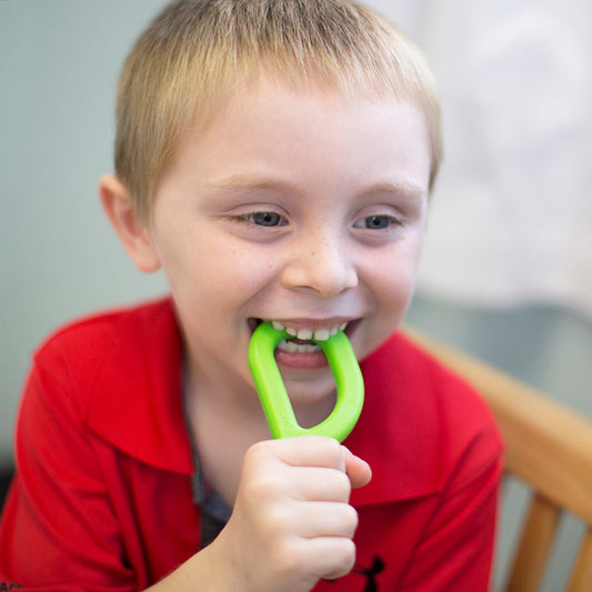child using green ark grabber for sensory regulation.