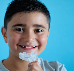 Smiling child holding Myo Munchee Junior – promotes healthy oral habits, chewing coordination, and functional muscle tone in kids