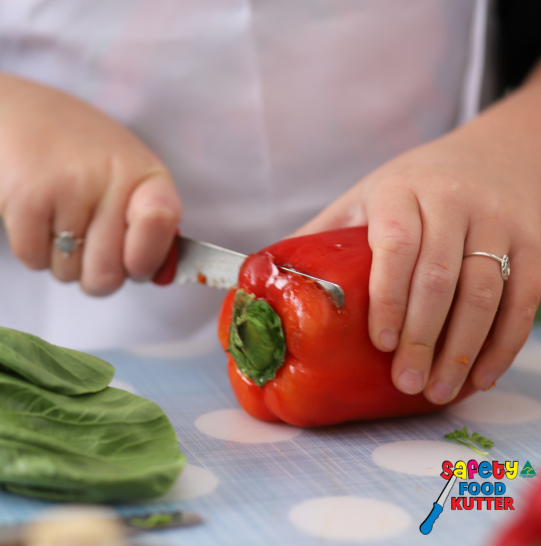 Child practising food cutting skills using safety knife on capsicum – safe learning activity supporting therapy goals and potentially NDIS-funded