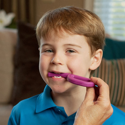 child using magenta ARK grabber as an oral motor and sensory tool. May be NDIS funded.