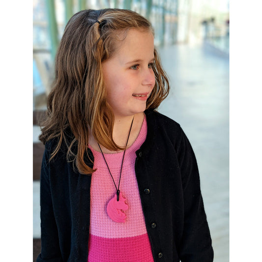 child wearing hot pink ARK Chewnicorn Sensory Chew Necklace chew tool for sensory seeking kids.