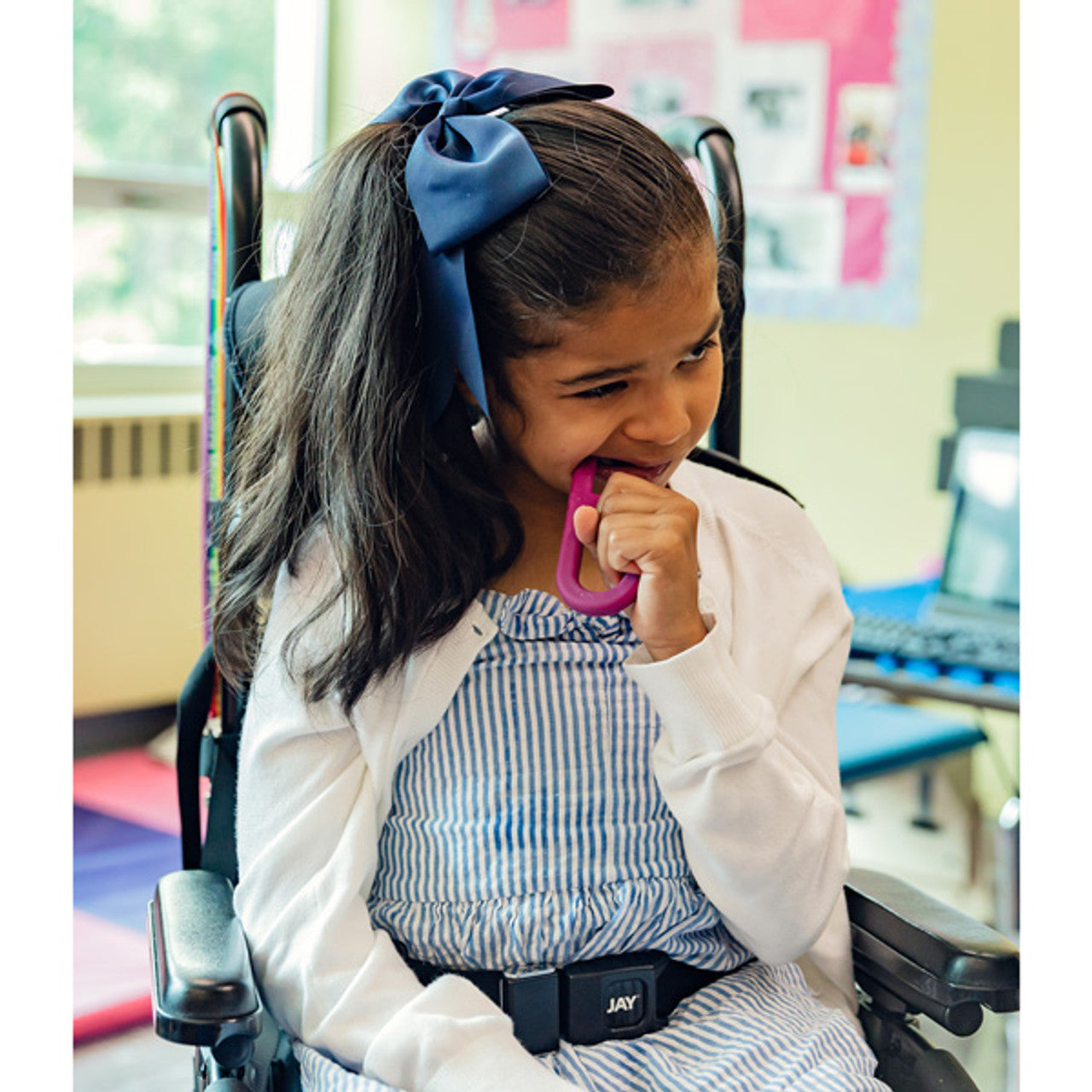 girl using magenta ARK grabber as an oral motor and sensory tool. May be NDIS funded.