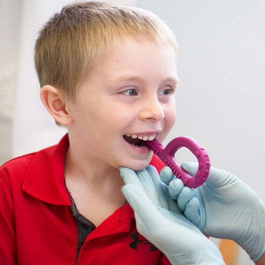 child using purple ARK grabber oral motor chew tool for sensory needs. May be NDIS funded.