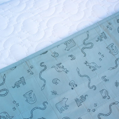 Light blue quilt with animal pattern on a textured white background. Bedwetting Brolly Sheets - Animal Kingdom
