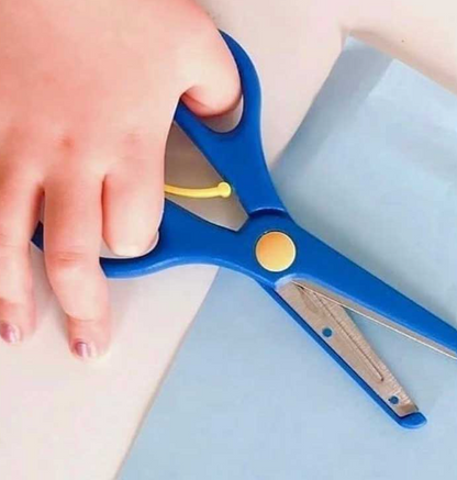 Close-up of a child’s hand grasping blue safety scissors with spring support, promoting correct cutting technique and confidence in young learners; potentially NDIS-funded