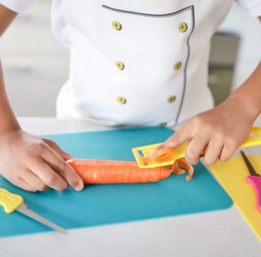 Child using KiddieKutter safety peeler to peel a carrot – encouraging meal prep independence and fine motor development; potentially NDIS-funded