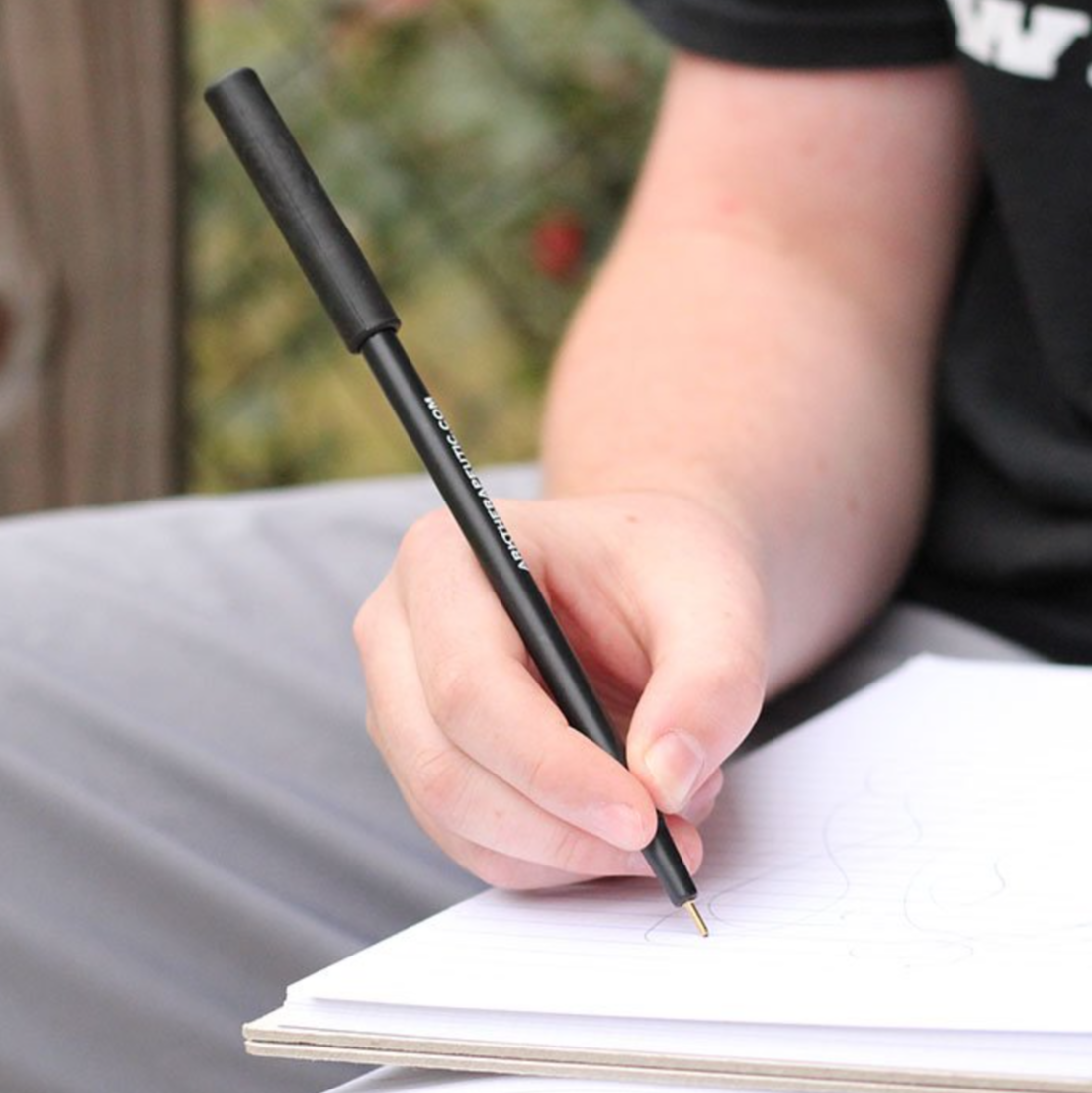 Child writing with ARK Krypto-Bite Chewable Pencil Topper for focus and sensory regulation. Suitable for NDIS plans