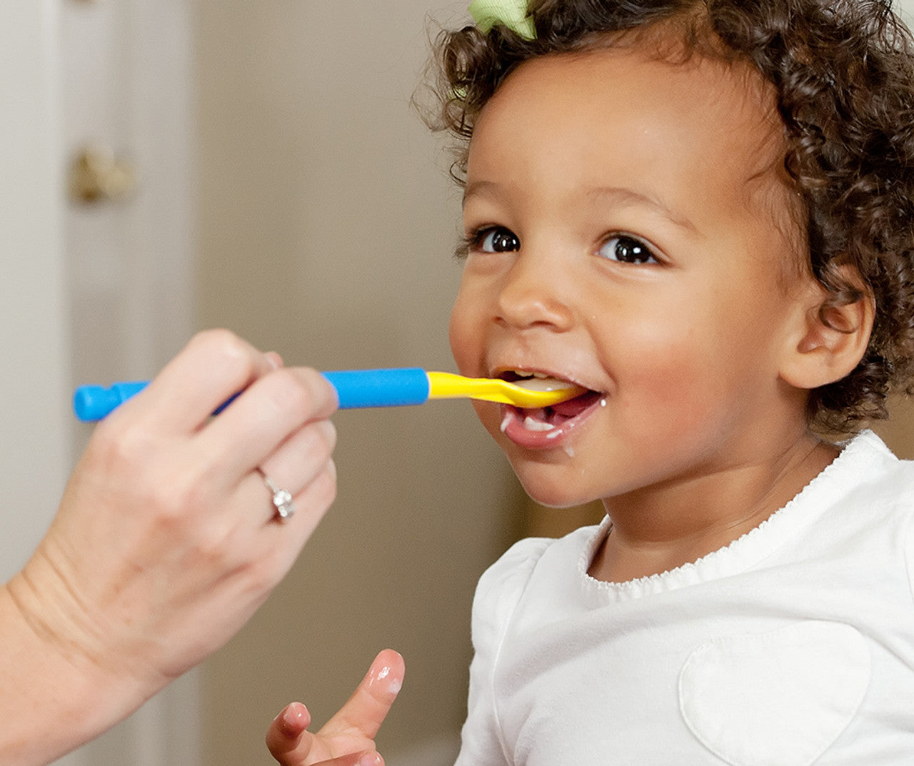 Child using the yellow ARK Spoon Tip for the Z-Vibe® (Textured). spoon to help child feeding that has difficulty. Has textured sides on the spoon.